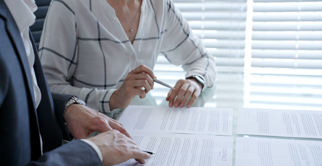Client complétant la section clause bénéficiaire d'un formulaire d'assurance vie avec l'accompagnement d'un conseiller pointant les mentions importantes